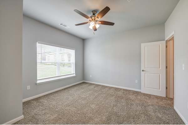 an empty room with a ceiling fan and a window